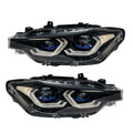 A pair of modern car headlight assemblies shown against a plain white background. The headlight housings are black with silver chrome accents and blue LED light rings around the projector lenses.