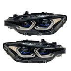 A pair of modern car headlight assemblies shown against a plain white background. The headlight housings are black with silver chrome accents and blue LED light rings around the projector lenses.
