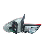 A rear-view side mirror assembly with the outer housing removed, showing the internal glass, wiring, and mounting hardware against a plain light gray wall.
